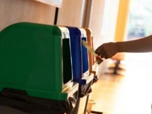 Una persona butta un imballaggio all'interno di un bidone della raccolta differenziata Una persona butta un imballaggio all'interno di un bidone della raccolta differenziata