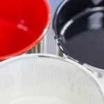 tre barattoli aperti di vernice, rossa, bianca e nera