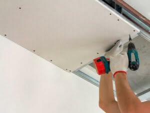 Operaio durante l'installazione di una lastra in cartongesso sul soffitto