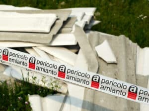 nastro di pericolo presenza amianto con pezzi di manufatti fibrocemento sullo sfondo nastro di pericolo presenza amianto con pezzi di manufatti fibrocemento sullo sfondo