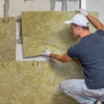 Operaio rimuove dal muro di un edificio materiale isolante