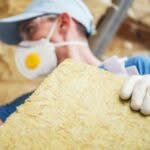 Operaio con mascherina e occhiali protettivi tiene lastra di materiale isolante